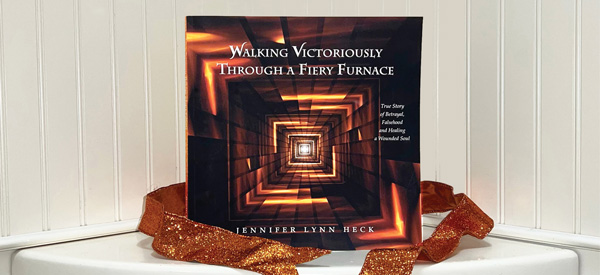 Jennifer Lynn Heck’s 2023 book, Walking Victoriously Through a Fiery Furnace, sitting on an ivory shelf with a glittering orange ribbon. Click to go to book’s page on Amazon.