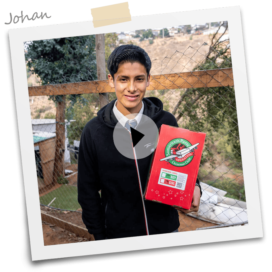 Johan outside smiling and holding an Operation Christmas Child shoebox